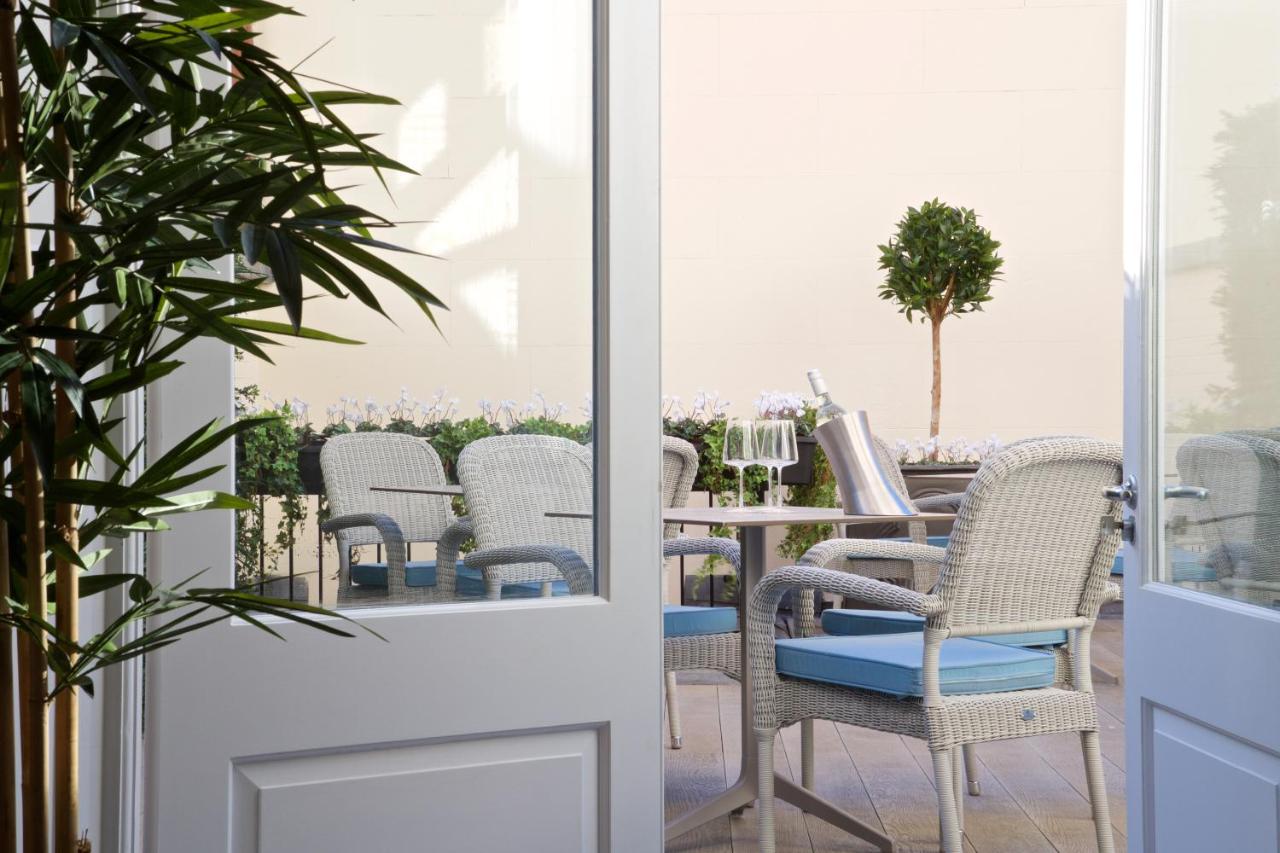 a patio with wicker chairs and a table at 54 Queen's Gate Hotel in London