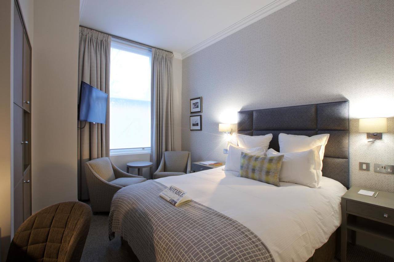 a hotel room with a bed and a chair at 54 Queen's Gate Hotel in London