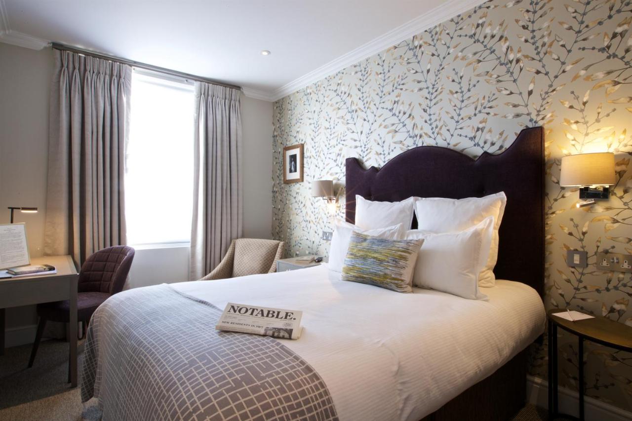 a hotel room with a bed with a book on it at 54 Queen's Gate Hotel in London